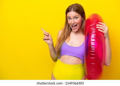 Young caucasian woman holding air mattress isolated on yellow background surprised and pointing finger to the side - Powered by Shutterstock