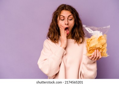 Young Caucasian Woman Holding A Bag Of Chips Isolated On Purple Background Is Saying A Secret Hot Braking News And Looking Aside