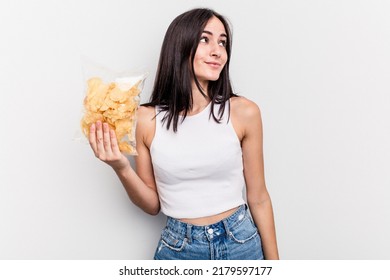 Young caucasian woman holding a bag of chips isolated on white background dreaming of achieving goals and purposes