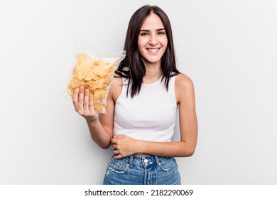 Young Caucasian Woman Holding A Bag Of Chips Isolated On White Background Laughing And Having Fun.