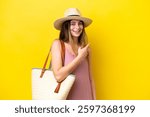Young caucasian woman holding a beach bag isolated on yellow background pointing to the side to present a product