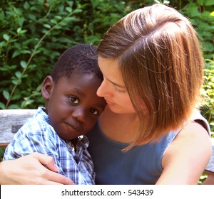 Young Caucasian Woman Holding A Beautiful African American Child.