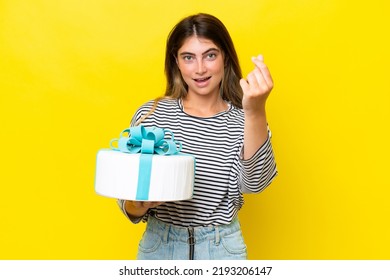 Young Caucasian Woman Holding Birthday Cake Isolated On Yellow Background Making Money Gesture