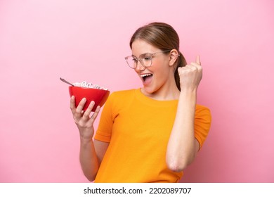 Young Caucasian Woman Holding A Bowl Of Cereals Isolated On Pink Background Celebrating A Victory