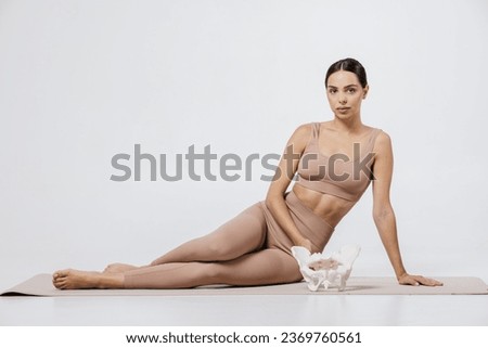 Young caucasian woman holding the female pelvis sample in the hands. Healthy woman. Gynecology, healthcare, medicine. Body, bones concept