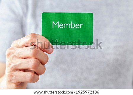 A young caucasian woman is holding a green card that says member on it. A customizable image which has space for text to be inserted. Being a member, membership dues, subscription, group concepts.