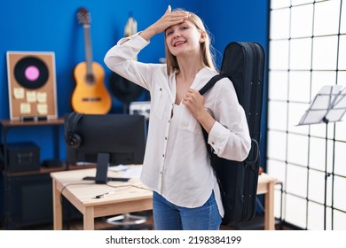 Young Caucasian Woman Holding Guitar Case Stressed And Frustrated With Hand On Head, Surprised And Angry Face 