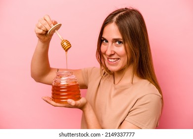 Young Caucasian Woman Holding Honey Isolated On Pink Background