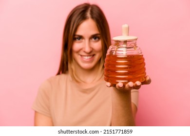 Young Caucasian Woman Holding Honey Isolated On Pink Background