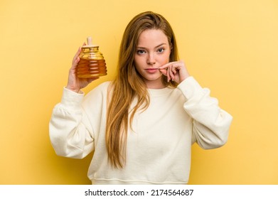 Young Caucasian Woman Holding A Honey Isolated On Yellow Background With Fingers On Lips Keeping A Secret.