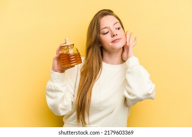 Young Caucasian Woman Holding A Honey Isolated On Yellow Background Trying To Listening A Gossip.