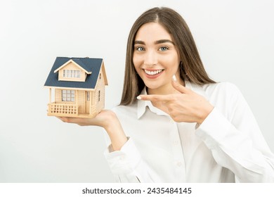 Young caucasian woman holding a house model isolated on white background - Powered by Shutterstock