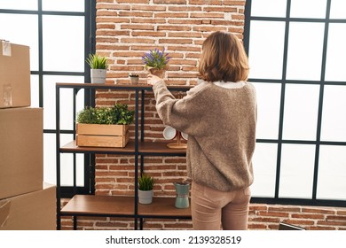 Young Caucasian Woman Holding Lavender Plant Pot At New Home