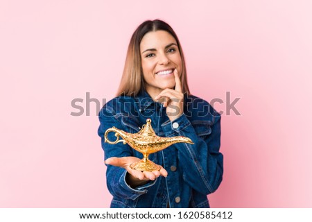 Young caucasian woman holding a magic lamp isolated