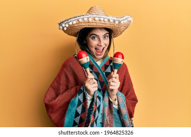 Young caucasian woman holding mexican hat using maracas celebrating crazy and amazed for success with open eyes screaming excited. 