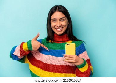 Young Caucasian Woman Holding Mobile Phone Isolated On Blue Background Person Pointing By Hand To A Shirt Copy Space, Proud And Confident