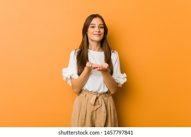 Young Caucasian Woman Holding Something With Palms, Offering To Camera.