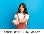 Young caucasian woman isolated on blue background holding copyspace imaginary on the palm to insert an ad