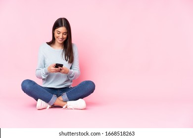 Young caucasian woman isolated on pink background sending a message with the mobile - Shutterstock ID 1668518263
