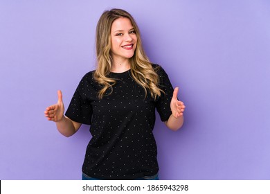 Young caucasian woman isolated on purple background holding something with both hands, product presentation. - Shutterstock ID 1865943298