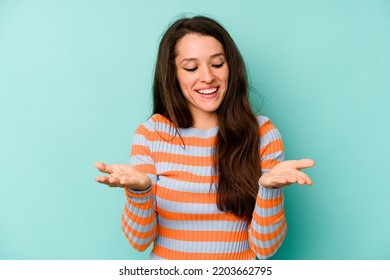 Young Caucasian Woman Isolated On Blue Background Holding Something With Palms, Offering To Camera.