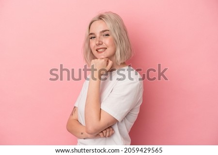Young caucasian woman isolated on pink background smiling happy and confident, touching chin with hand.