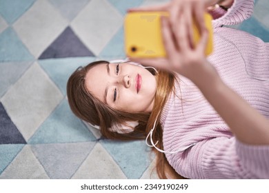 Young caucasian woman listening to music lying on floor at home - Powered by Shutterstock