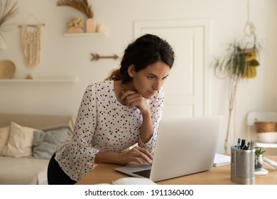 Young Caucasian woman look at laptop screen work distant on gadget from home office. Millennial female use computer shopping online or browsing wireless internet on device. Technology concept. - Shutterstock ID 1911360400