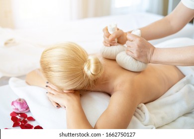 young caucasian woman lying on white spa bed. Poultice hot herbal massage in spa salon by professional Thai masseuse. Hot Compress Massage is Thai massage which is the world famous