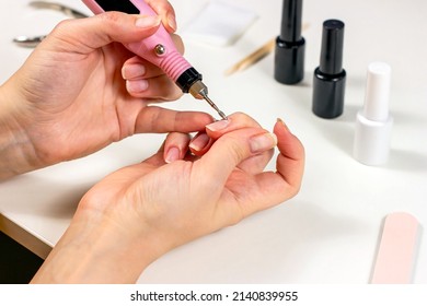 Young Caucasian Woman Making Self Manicure At Home With The Help Of Electrical Fraser Machine And Other Tools For Nail Procedures