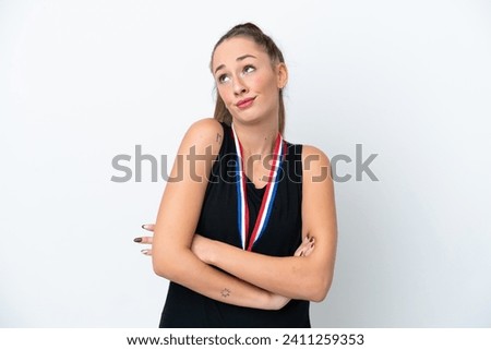 Young caucasian woman with medals isolated on white background making doubts gesture while lifting the shoulders