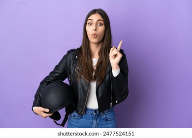 Young caucasian woman with a motorcycle helmet isolated on purple background intending to realizes the solution while lifting a finger up - Powered by Shutterstock