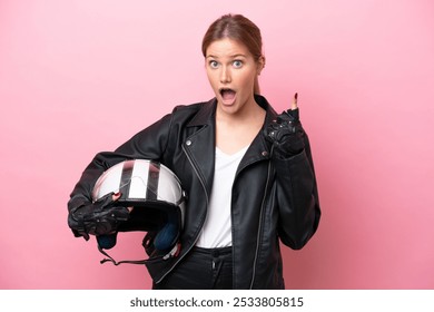 Young caucasian woman with a motorcycle helmet isolated on pink background thinking an idea pointing the finger up