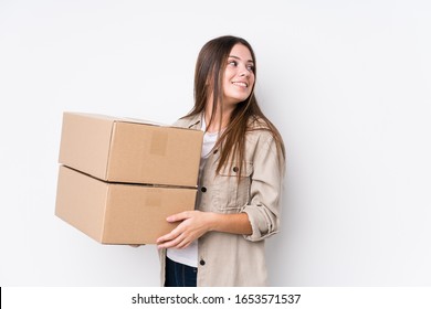 Young caucasian woman moving to a new home looks aside smiling, cheerful and pleasant.