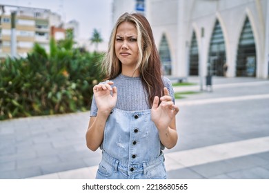 Young Caucasian Woman Outdoors Disgusted Expression, Displeased And Fearful Doing Disgust Face Because Aversion Reaction. With Hands Raised 