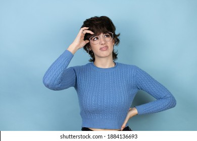 Young caucasian woman over isolated blue background confuse and wonder about question. Uncertain with doubt, thinking with hand on head - Shutterstock ID 1884136693