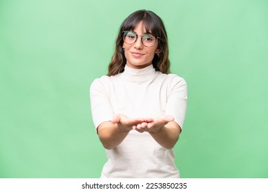 Young caucasian woman over isolated background holding copyspace imaginary on the palm to insert an ad