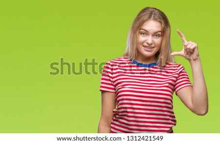 Young caucasian woman over isolated background smiling and confident gesturing with hand doing size sign with fingers while looking and the camera. Measure concept.