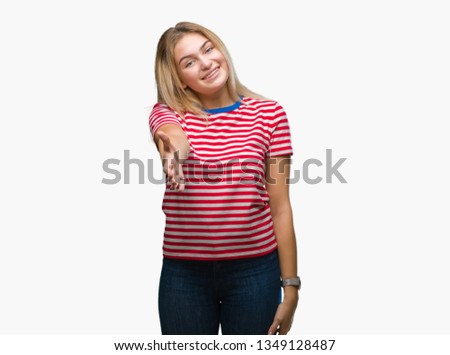 Young caucasian woman over isolated background smiling friendly offering handshake as greeting and welcoming. Successful business.