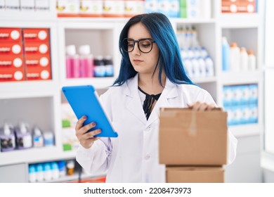 Young caucasian woman pharmacist using touchpad holding packages at pharmacy - Shutterstock ID 2208473973