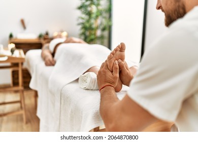 Young caucasian woman at physiotherapy clinic getting muscle massage by professional therapist. Physiotherapist man massaging feet to client - Powered by Shutterstock