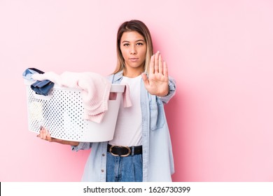 Young Caucasian Woman Picking Up A Dirty Clothes Standing With Outstretched Hand Showing Stop Sign, Preventing You.