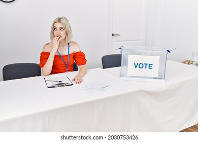 Young Caucasian Woman At Political Election Sitting By Ballot Looking Stressed And Nervous With Hands On Mouth Biting Nails. Anxiety Problem. 