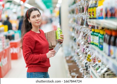 A young Caucasian woman poses with seedling pots, flower seeds and plant fertilizer in her hands. Concept of gardening and preparation for the garden season