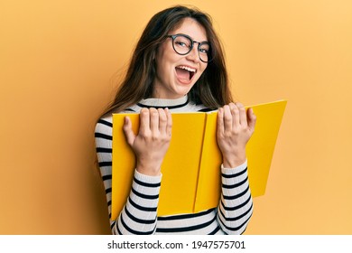 Young Caucasian Woman Reading A Book Wearing Glasses Smiling And Laughing Hard Out Loud Because Funny Crazy Joke. 