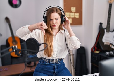 Young Caucasian Woman Recording Song At Music Studio With Angry Face, Negative Sign Showing Dislike With Thumbs Down, Rejection Concept 