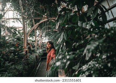 young caucasian woman in red jacket walking calmly relaxed inside lonely quiet botanic garden caressing plants, botanic garden christchurch, new zealand - Shutterstock ID 2311551601