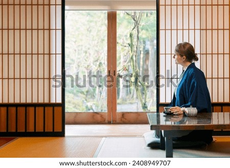 A young caucasian woman is relaxing at a traditional Japanese drinking a tea
