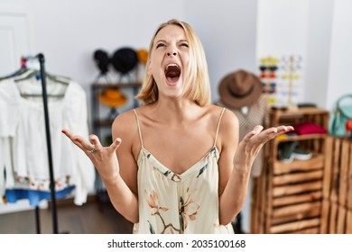 Young caucasian woman at retail shop crazy and mad shouting and yelling with aggressive expression and arms raised. frustration concept. 
