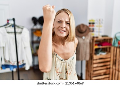 Young caucasian woman at retail shop angry and mad raising fist frustrated and furious while shouting with anger. rage and aggressive concept. 